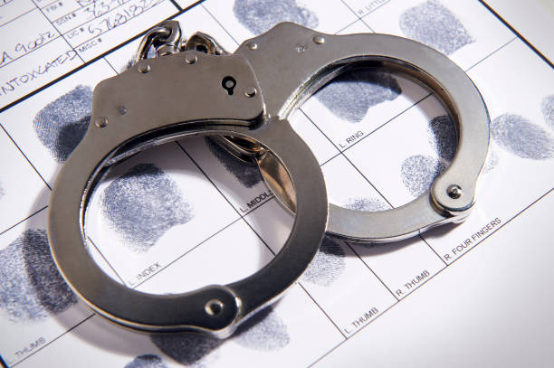 Handcuffs laying on top of fingerprint chart in file Handcuffs laying on top of fingerprint chart in file handcuffs stock pictures, royalty-free photos & images