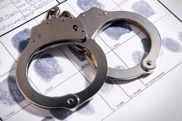 наручники, лежащие на верхней части диаграммы отпечатков пальцев в файле - преступление стоковые фото и изображения