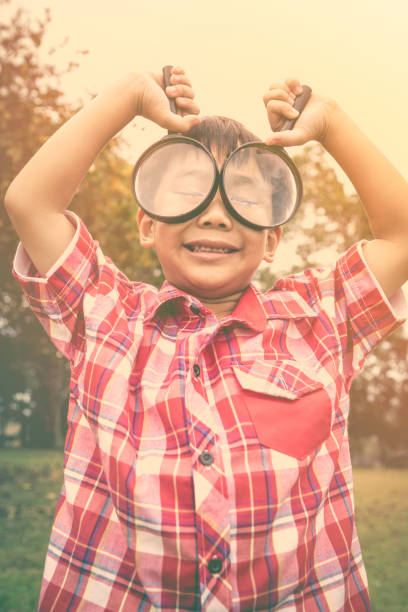 istock Asian boy with magnifying glass at park on vacation. 658011260