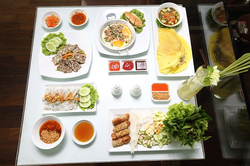 Vietnamese Food in Restaurant white plate on the Table with side dish, group many variety of meal, top view
