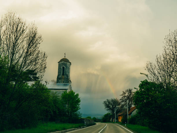 Rainbow in the sky above the church and road.