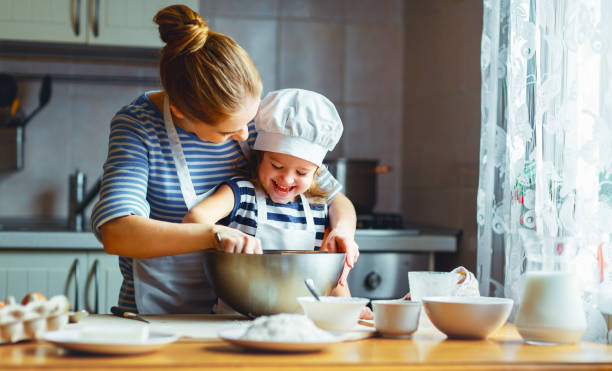 happy family im küche. mutter und kind vorbereiten teig, backen kekse - kuchen backen stock-fotos und bilder