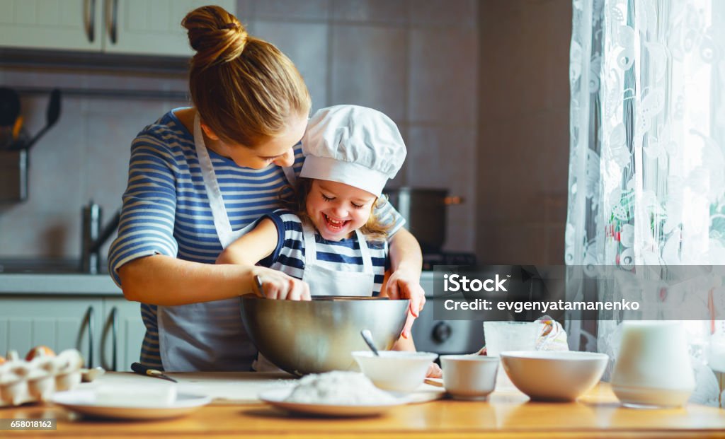Onnellinen perhe keittiössä. äiti ja lapsi valmistavat taikinaa, leipovat keksejä - Rojaltivapaa avainsanalla Ruoanlaitto ja tyyppiä Kuvapankin valokuva