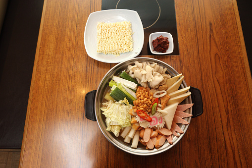 Korea Food in Restaurant on wooden table, kimchi hot pot with instant noodle vegetable spicy sauce soup