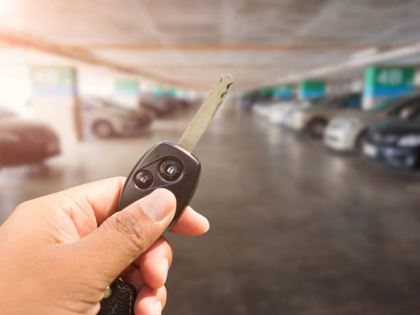 Car key in hand on parking car background stock photo