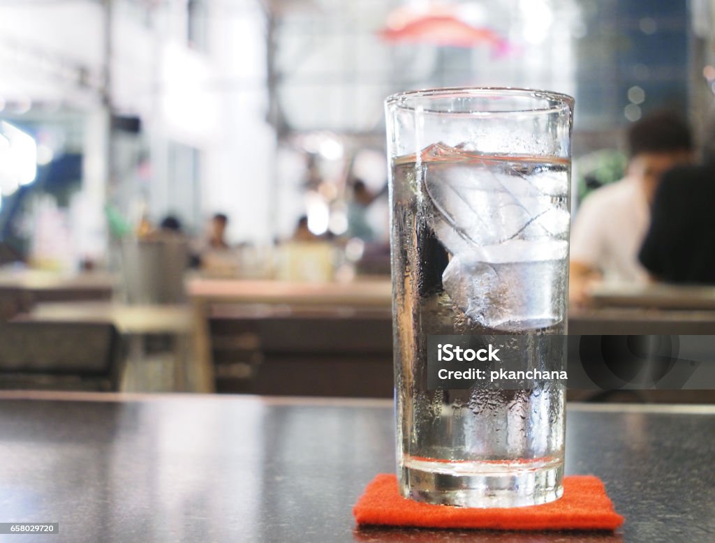 Glass of water with ice on the table in restaurant at night Water Stock Photo