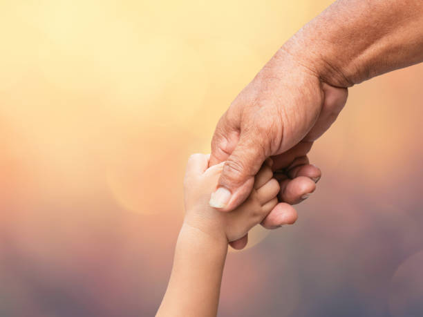 Father holding baby hand finger on blurred bokeh background stock photo