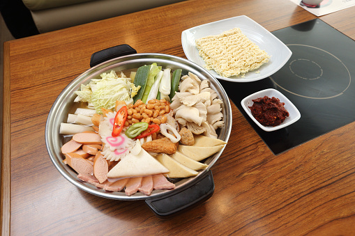 Korea Food in Restaurant on wooden table, kimchi hot pot with instant noodle vegetable spicy sauce soup