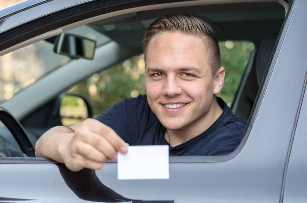istock Young man leaning from a car showing his licence 658052302