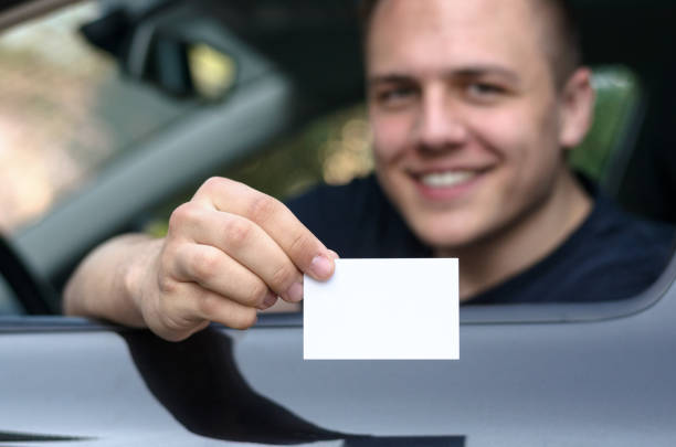 istock Young man leaning from a car showing his licence 658054812