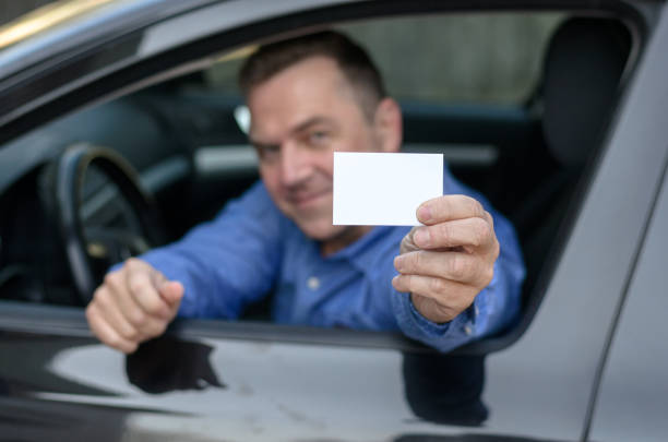 istock Middle aged man leaning from a car showing his licence 658054920