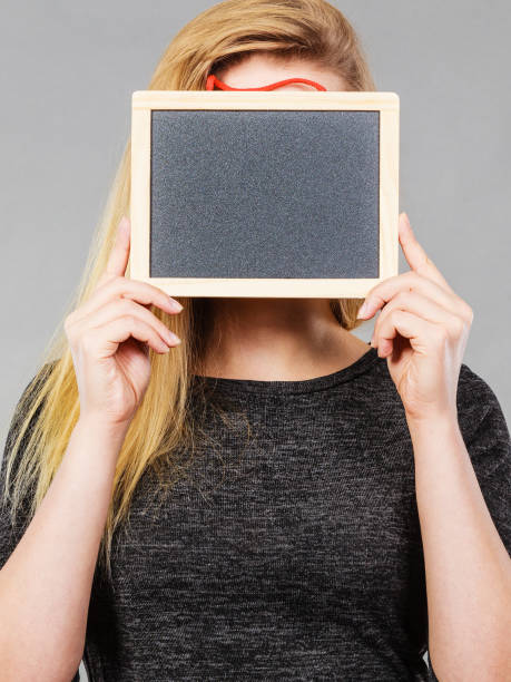 istock Woman holding blank black board on face 658074736