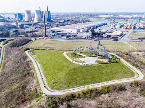 DUISBURG / GERMANY - MARCH 24 2017 : Landmark Tiger and Turtle standing on a hill while HKM is producing steel in the background, aerial