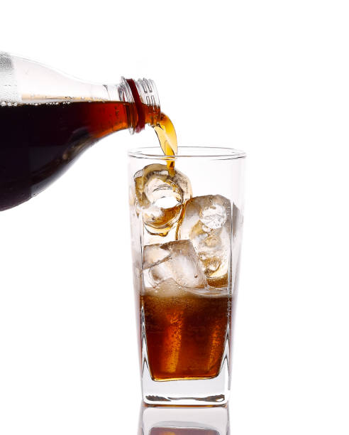 istock Pouring cola from bottle into glass isolated on white background 658074994