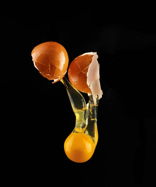 istock Yolk dropping from cracked raw egg divided by woman hands. 658083400