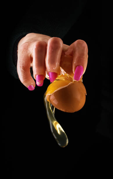 istock Yolk dropping from cracked raw egg divided by woman hands. 658085732