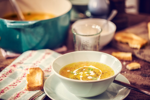Eating delicious chicken soup with carrots, onions and parsnips. The soup is served with fresh grilled toast.