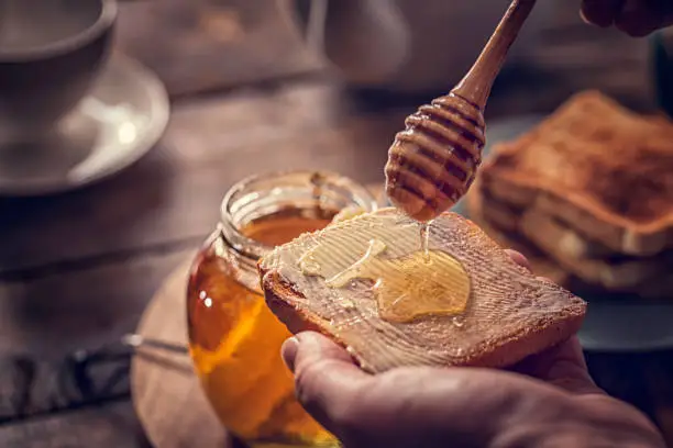 Preparing toast with butter and delicious honey for breakfast