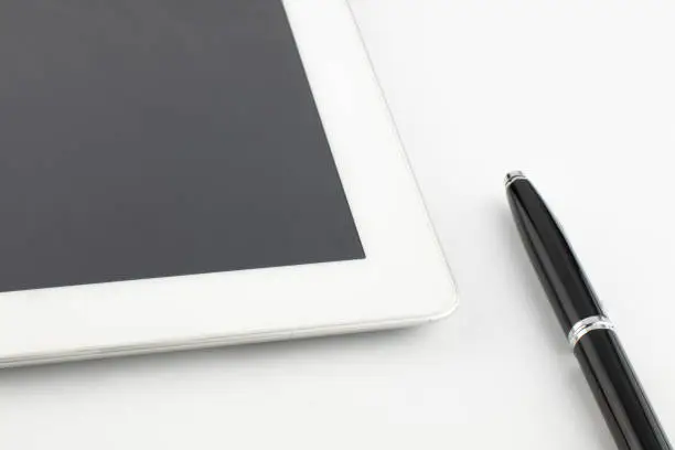 Tablet computer and a modern metal pen on a white background.