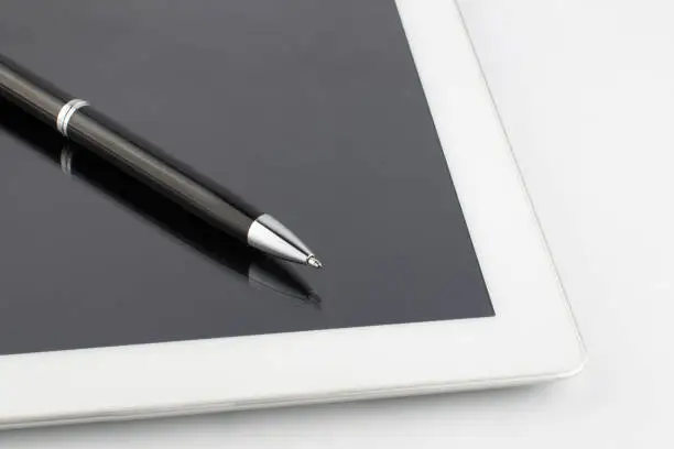 Tablet computer and a modern metal pen on a white background.