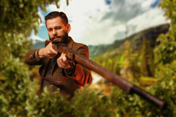 istock Hunter sitting in the bushes and aiming a rifle. 658114360