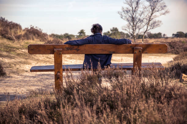 istock Woman sitting on a bench in nature 658114454