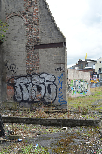 Dublin, Republic of Ireland, Ireland. September 30,2016. Old abandoned buildings with graffiti painted onto the walls in the city of Dublin, Ireland. Yard is littered with trash. Graffiti artist unknown.