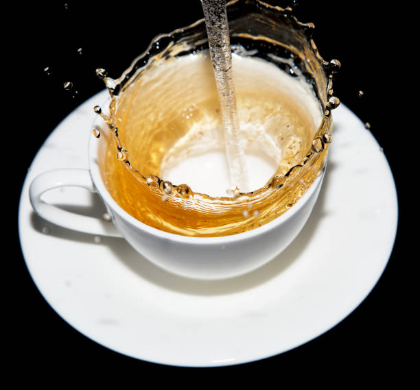 istock tea being poured into a saucer with splashes on a black background 658133378