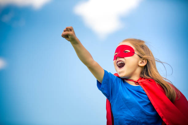 Funny little girl playing power super hero. Funny little girl playing power super hero over blue sky background. Superhero concept. guarding photos stock pictures, royalty-free photos & images