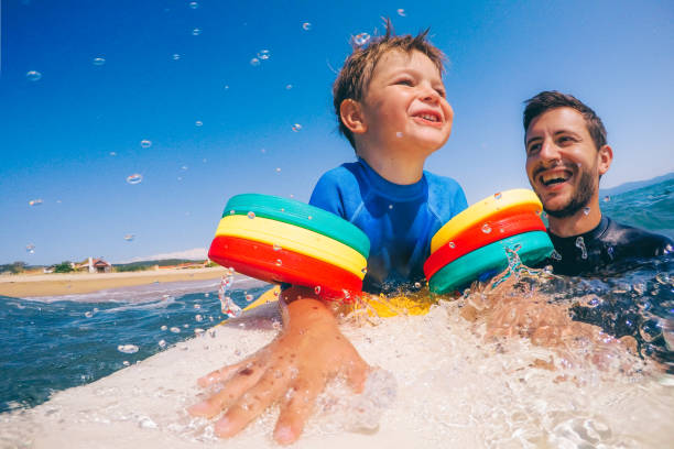 niño en tabla de surf - surfing beach family father fotografías e imágenes de stock