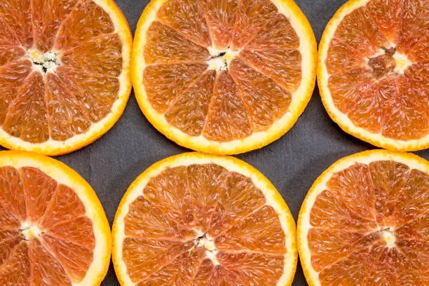 background and texture of fresh orange slices against gray slate stone