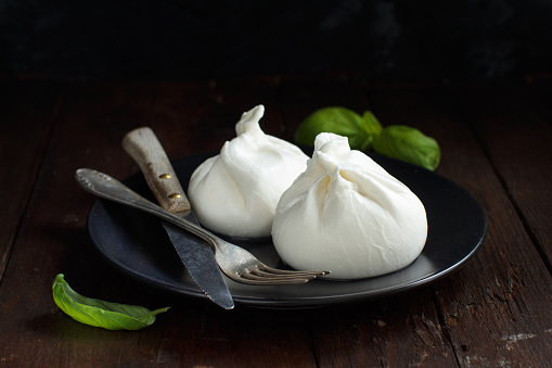 Italian cheese burrata with fork and knife on a dark background