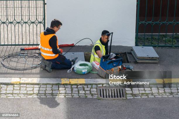 Team Of Workers Working On Implementation Of Fiber Optic Cables In Sewage System Stock Photo - Download Image Now