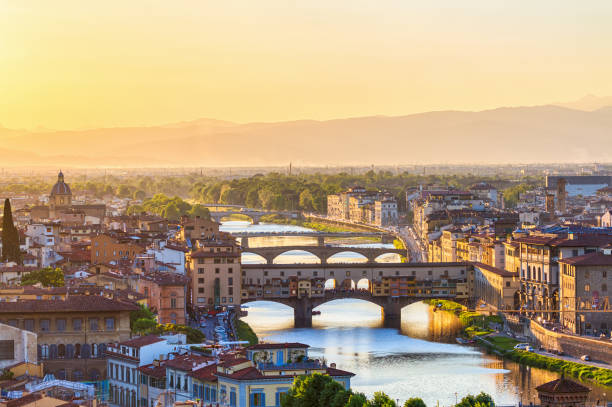 View of Florence at sunset with the Ponte Vecchio Bridge and the Arno River View of Florence at sunset with the Ponte Vecchio Bridge and the Arno River arch bridge photos stock pictures, royalty-free photos & images