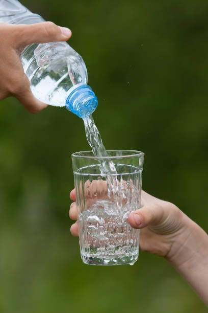 istock hand pouring water from bottle into glass 658173748