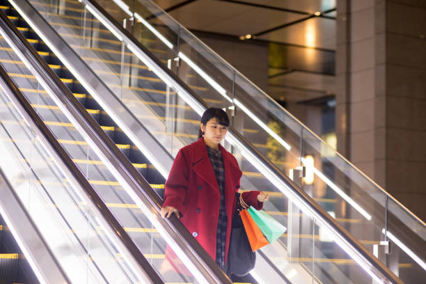 Young woman moving down on escalator after shopping