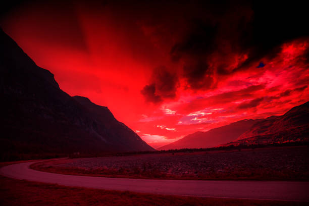Silhouette of mountains against burned evening sky. Beautiful fjord with dramatic red cloudy sky at sunset. Wild nature Norway.