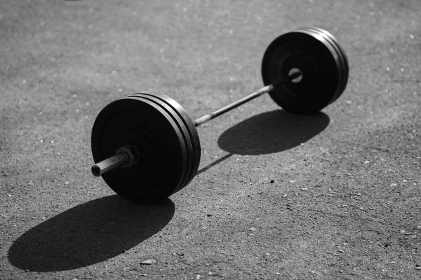istock Black barbell isolated on asphalt background 658178242