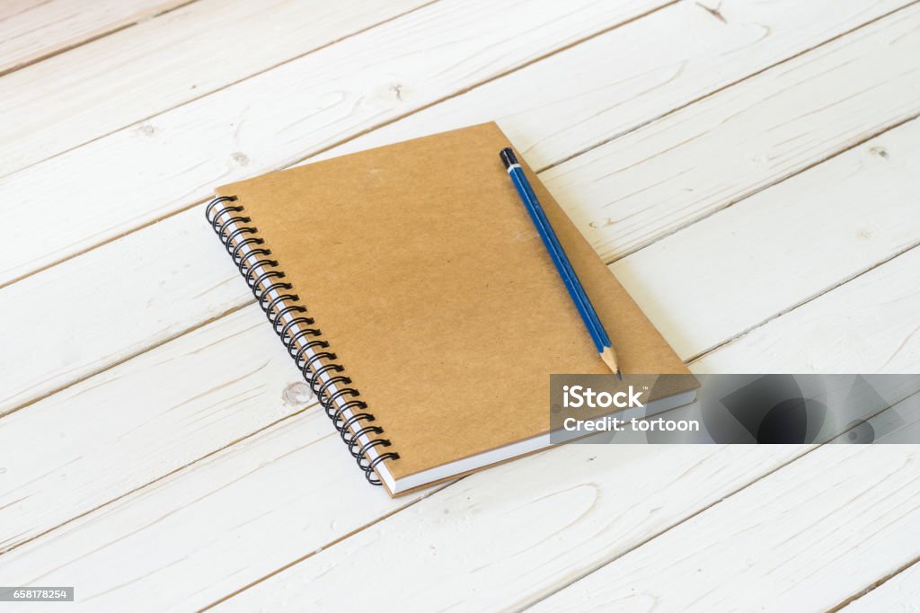 Brown notebook with blank pages and pencil on wood table Backgrounds Stock Photo