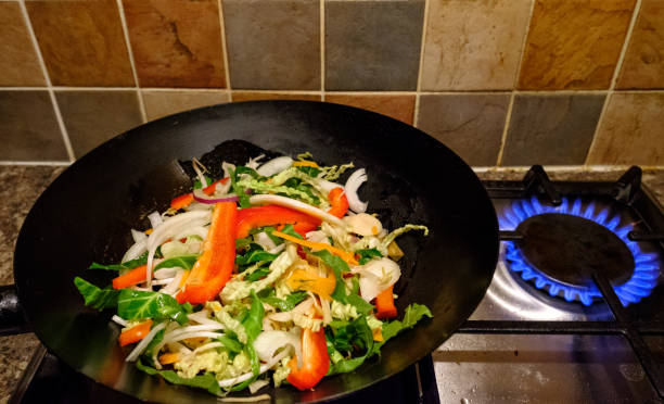 Freshly prepared Chinese meal seen having been cooked on a gas stove, shown being prepared in a modern kitchen during an evening. bluntisham, reino unido, 20 de febrero de 2017: comida china recién preparada que se ve preparada como parte de una cena. esta comida baja en calorías consiste principalmente en verduras frescas, parecen ser preparadas en una cocina moderna.