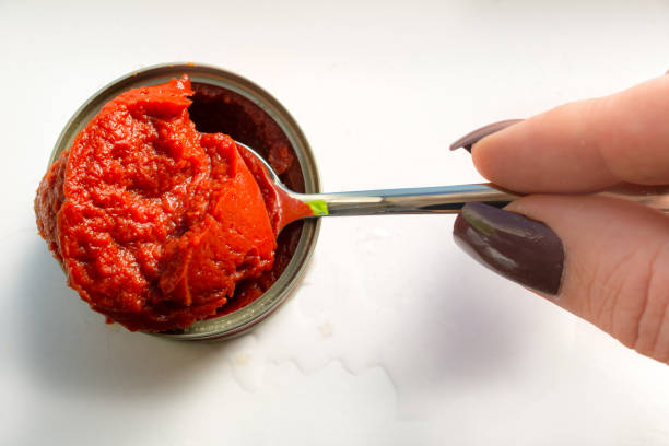 istock Woman holding a spoon with concentrated tomato paste 658188470