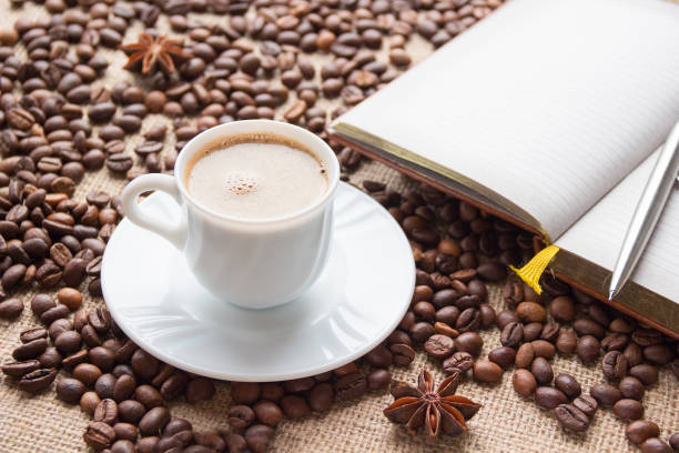 istock White coffee cup, notebook and pen on the background of the  coffee beans 658201580
