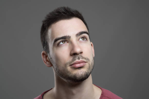 istock Close up of young handsome man face looking up thinking 658213340