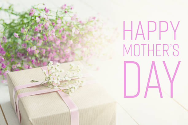 istock White wooden table with pink flowers and a present 658226758