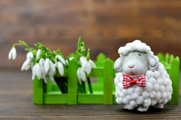 istock Spring flowers and cute sheep figurine on wooden background 658230426