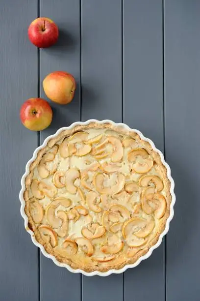 Apple tart with whole apples on grey stripped background vertical