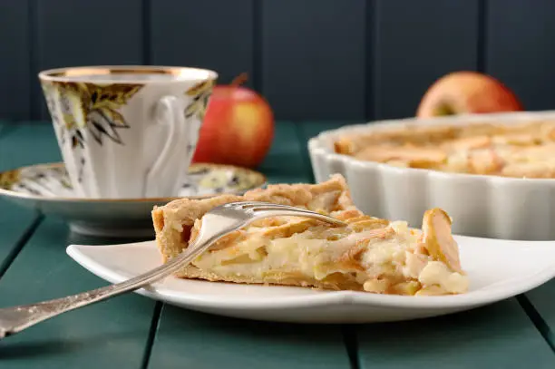 Apple tart with cup of tea and three whole apples closeup