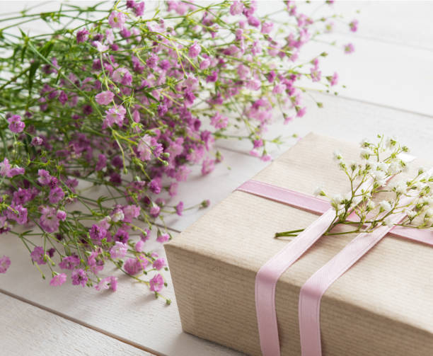 istock White wooden table with flowers and a present 658236806