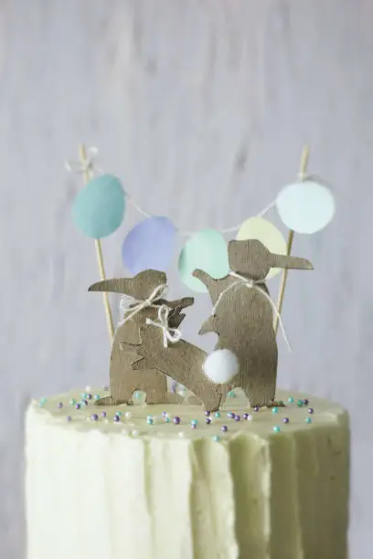 Photo of Easter themed wedding or birthday cake, with paper rabbit silhouettes as cake topper.