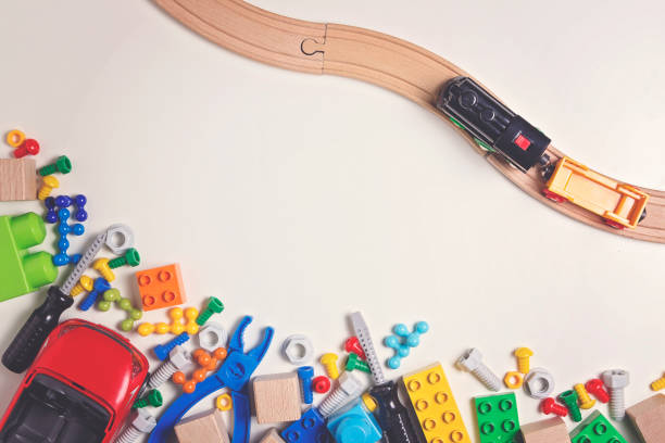 istock Colorful kids toys: plastic toy tools, bolts, nuts, car, train with wooden rail on white background as frame. Top view. 658247204